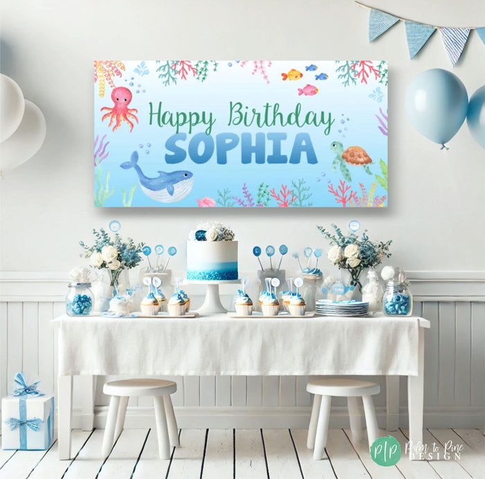 under the sea birthday banner in front of blue dessert table