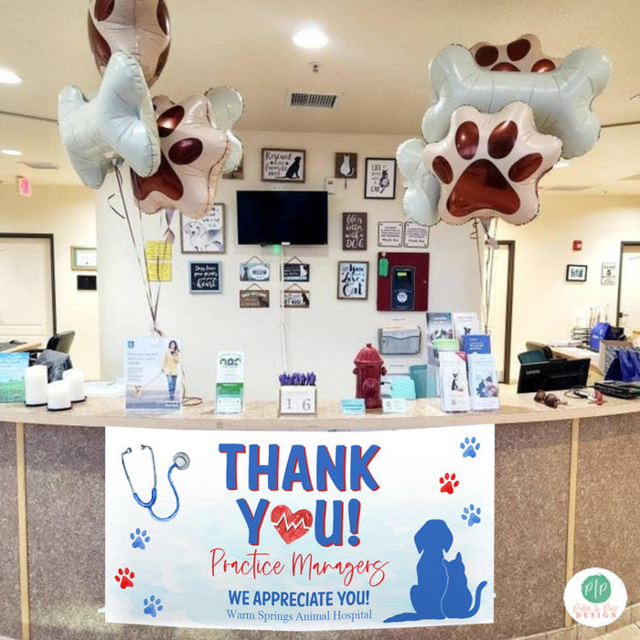 Animal hospital check in desk decorated for Staff Appreciation event featuring custom banner and helium balloons of dog prints and bones