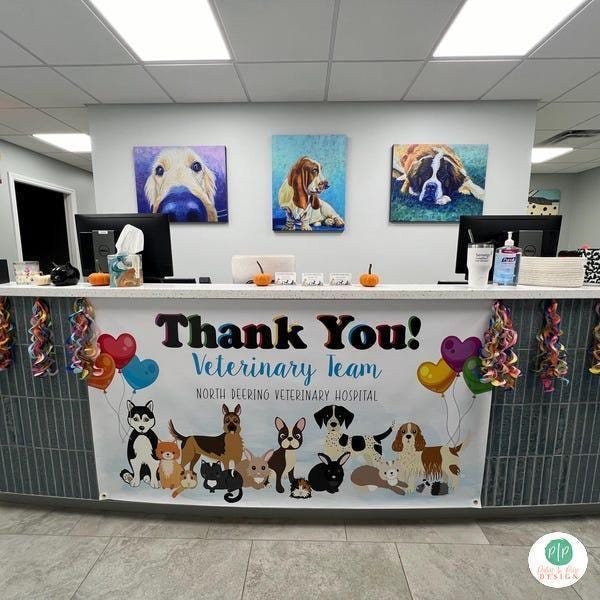 A large "THANK YOU! VETERINARY TEAM" banner, personalized with animal hospital name displayed on a reception desk with decorations