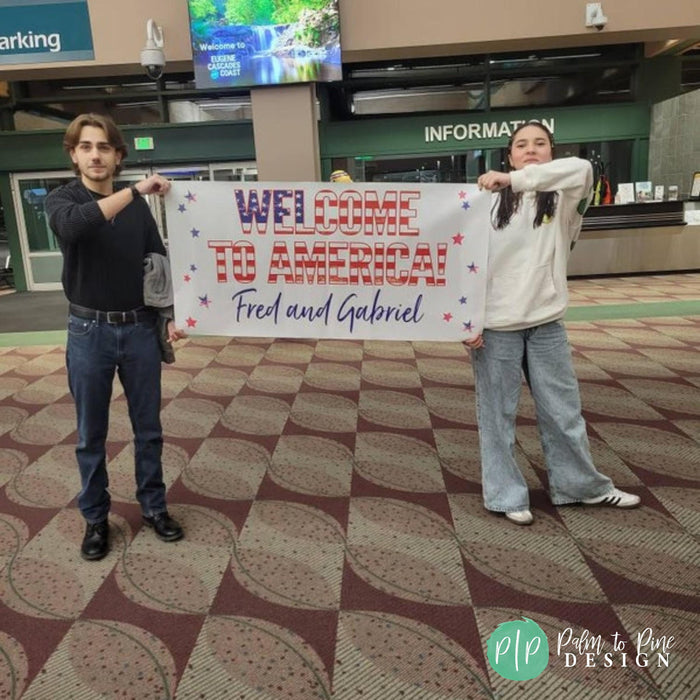 Two people holding a sign that says "Welcome to America" in front of a building with a "Welcome to America" sign.