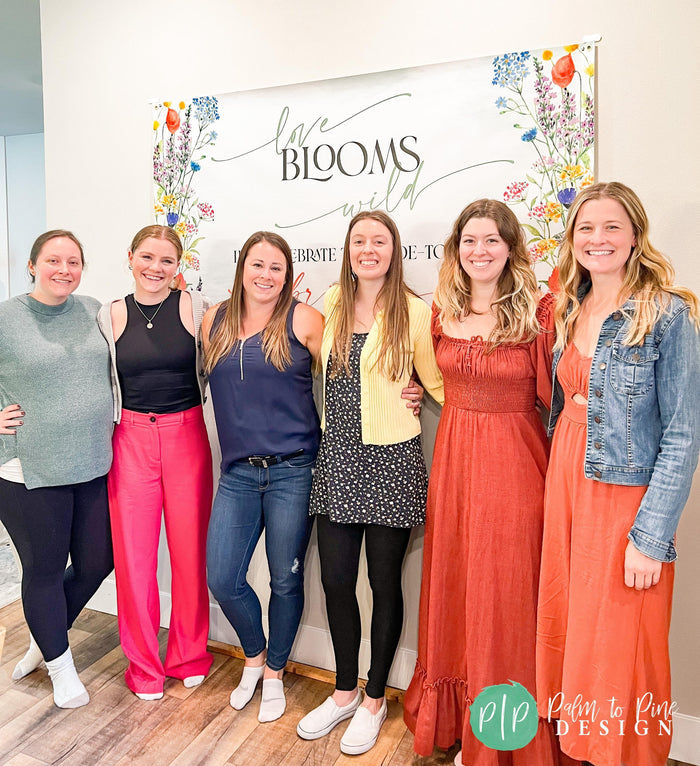 Watercolor floral bridal shower banner in green and white, personalized with the bride’s name and phrases 'Love Blooms Wild' and 'Let’s celebrate the bride-to-be' with bridesmaids