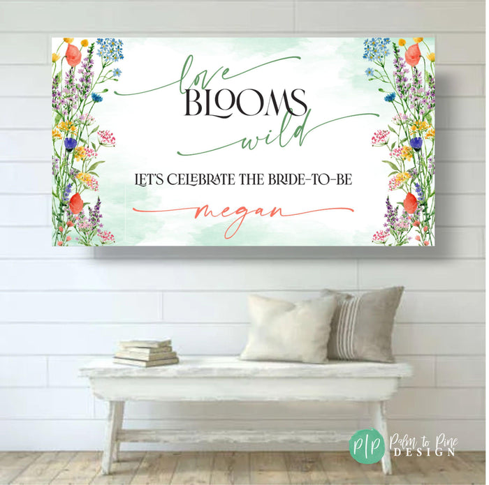Custom bridal shower banner with watercolor florals and the phrase 'Love Blooms Wild' in green and white, personalized with the bride-to-be’s name.