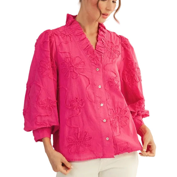 Woman wearing a bright pink embroidered blouse on a plain background