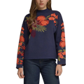 A woman modeling a navy blue crewneck sweater with vibrant orange and red floral patterns on the chest and sleeves, paired with dark blue jeans, set against a plain gray studio background.