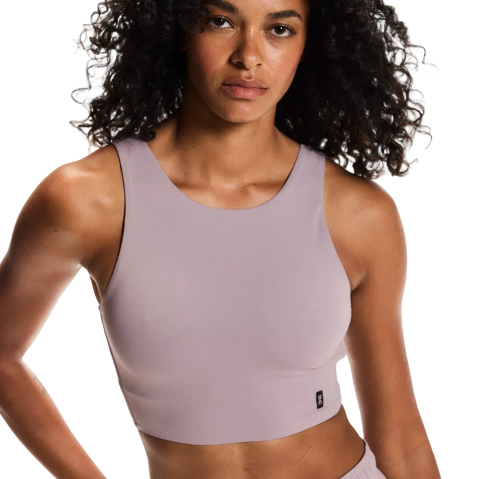 Woman wearing a light purple sports bra and shorts on a plain background
