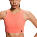 Woman wearing a coral sports bra against a white background
